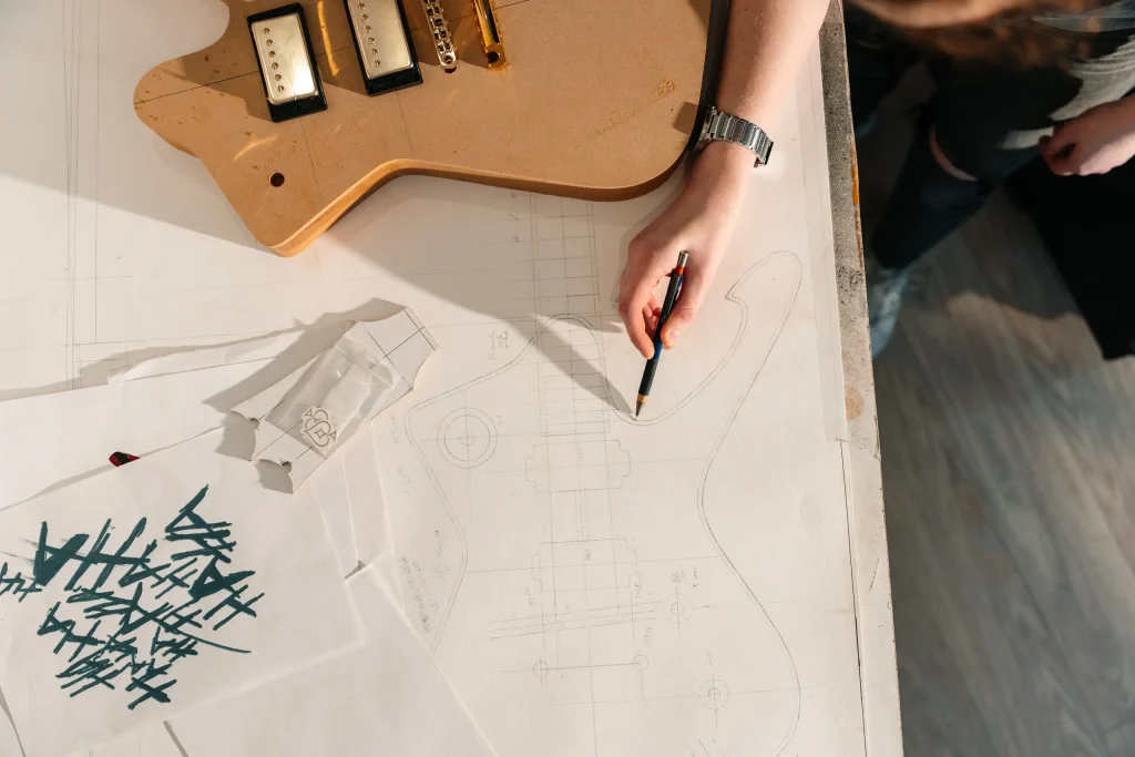 Luthier dessinant les plans d'une guitare électrique sur papier calque