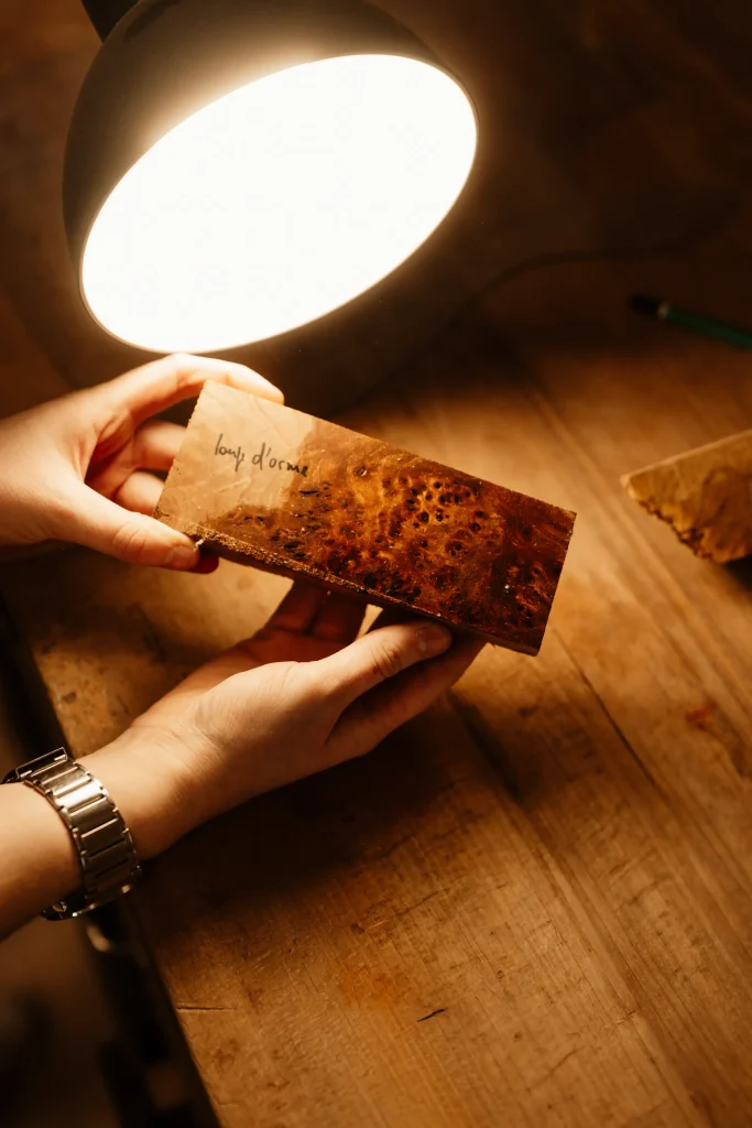 Luthier examinant un morceau de loupe d'orme sous une lampe d'atelier