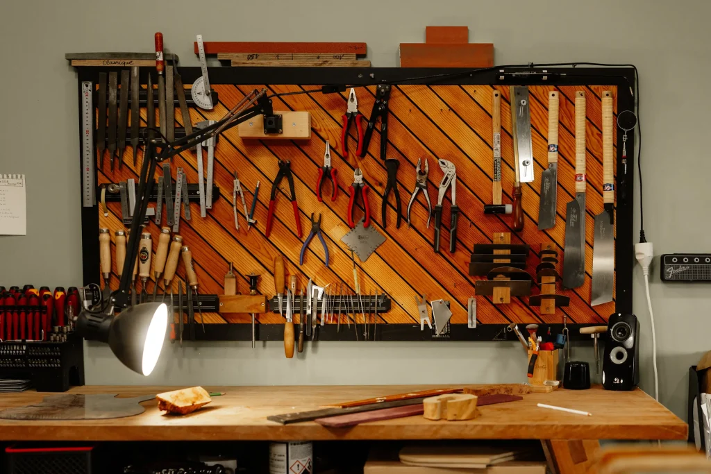 Panneau d'outils de lutherie organisés au-dessus d'un établi d'atelier
